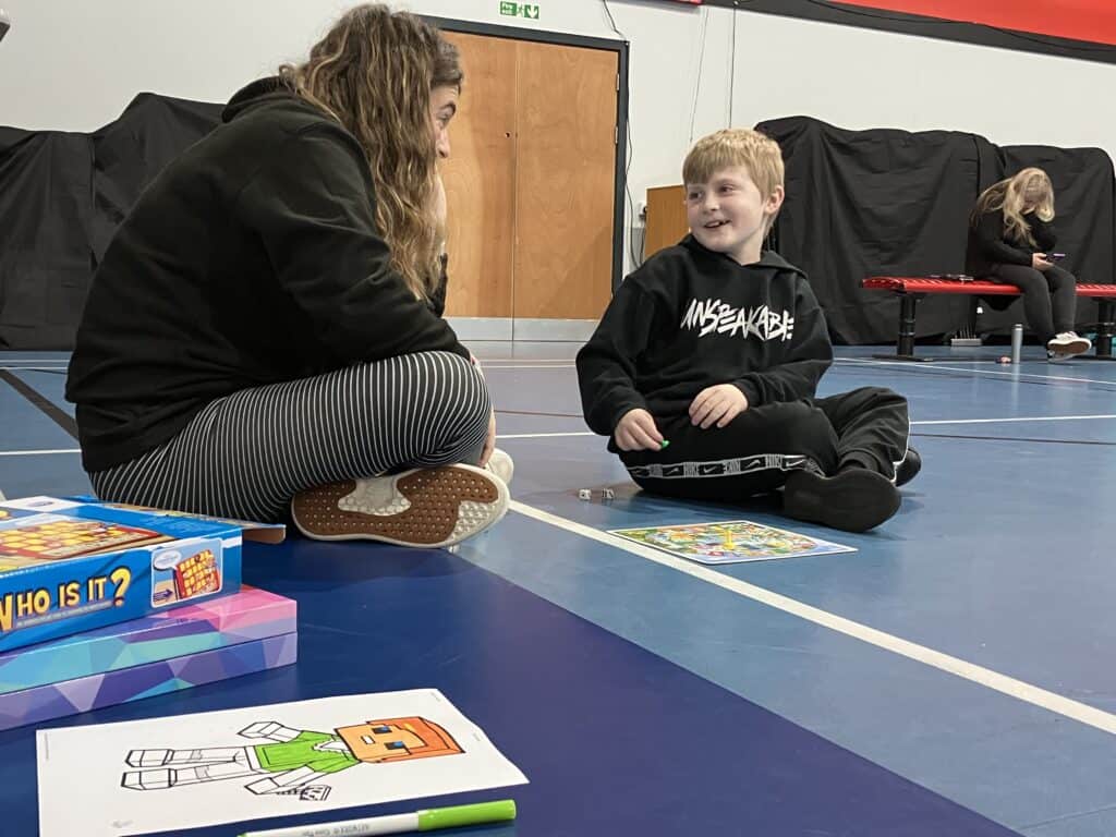 Staff member sitting on the floor reading books with a child during a SEND Stay and Play session